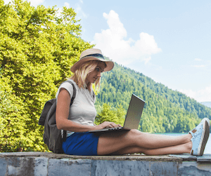 A woman uses a laptop while sitting outdoors