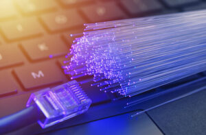A close-up of fiber-optic filaments, an Ethernet cable, and a keyboard