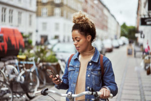 A woman with a bicycle is looking at her phone.