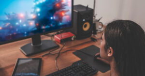 A black woman plays video games on a desktop computer