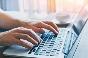 hands of person on using a laptop to find google fiber