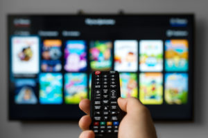 Man pointing remote toward TV and DVR