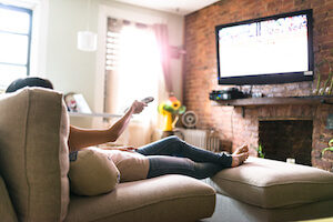 the 5 best cable tv and internet bundles - woman watching cable tv - reviews.org