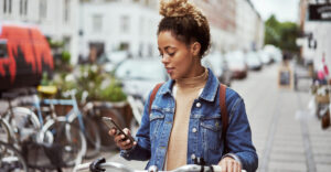 Shot of an attractive young woman using her cellphone while out cycling through the city
