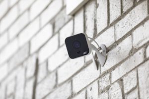 White ADT outdoor camera mounted on a white brick wall