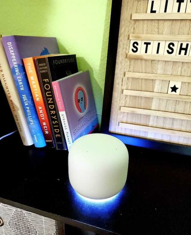 A Nest Wi-Fi point glows blue at its base to show the microphone is on