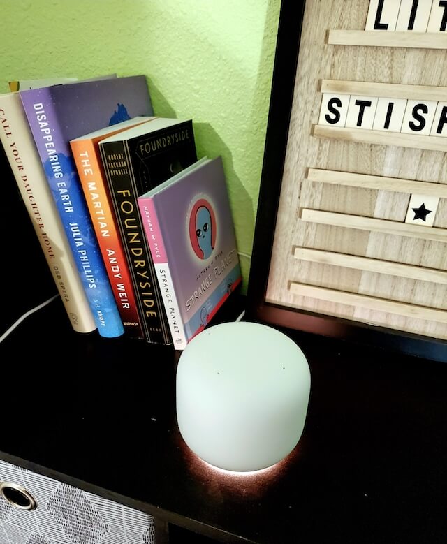 A Nest Wi-Fi point glows orange at its base to show the microphone is muted