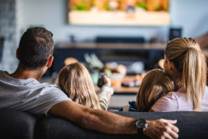 Dad, mom, daughter, and son sitting on couch watching Hulu TV