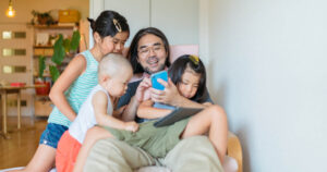 Dad on smartphone playing with kids