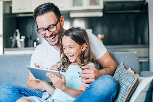 A father and daughter play games on a tablet together