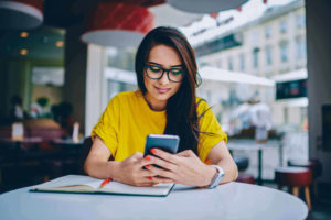 Woman sitting at a table using her smartphone.