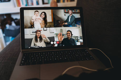 A laptop screen shows four family members on a Zoom video call