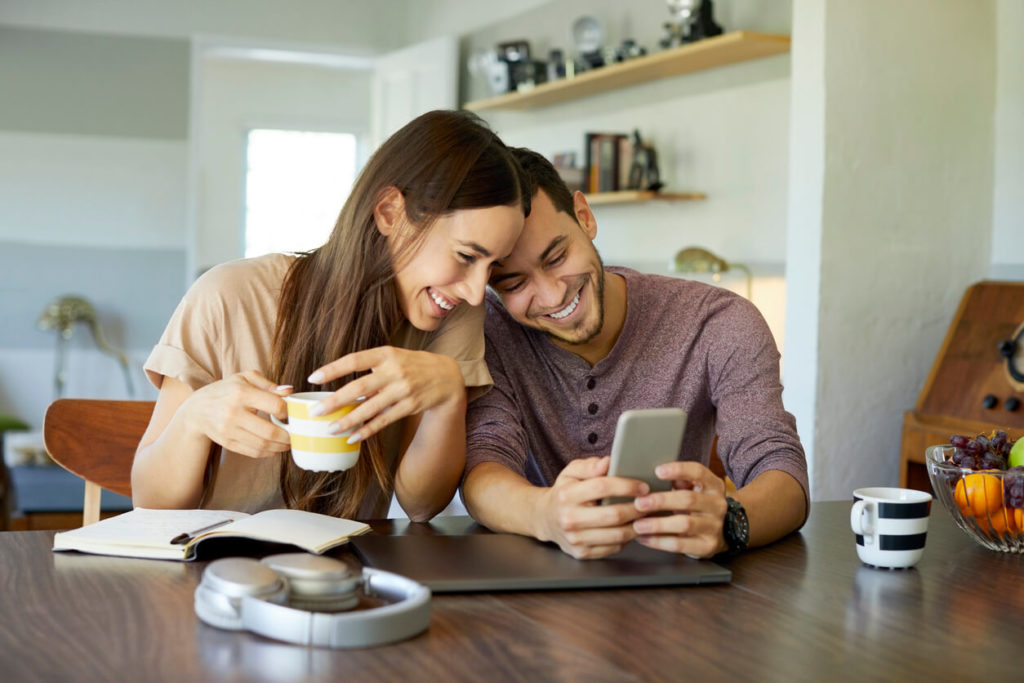 A young couple looks at a cell phone together.