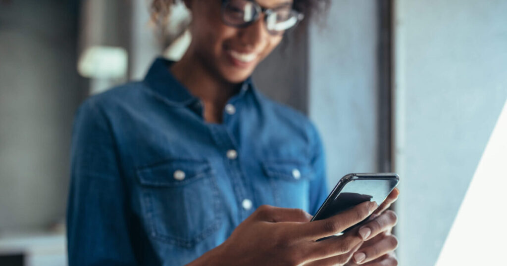 A business woman looks at her smartphone and smiles.