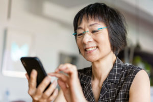 Senior age asian woman looks at a cell phone.