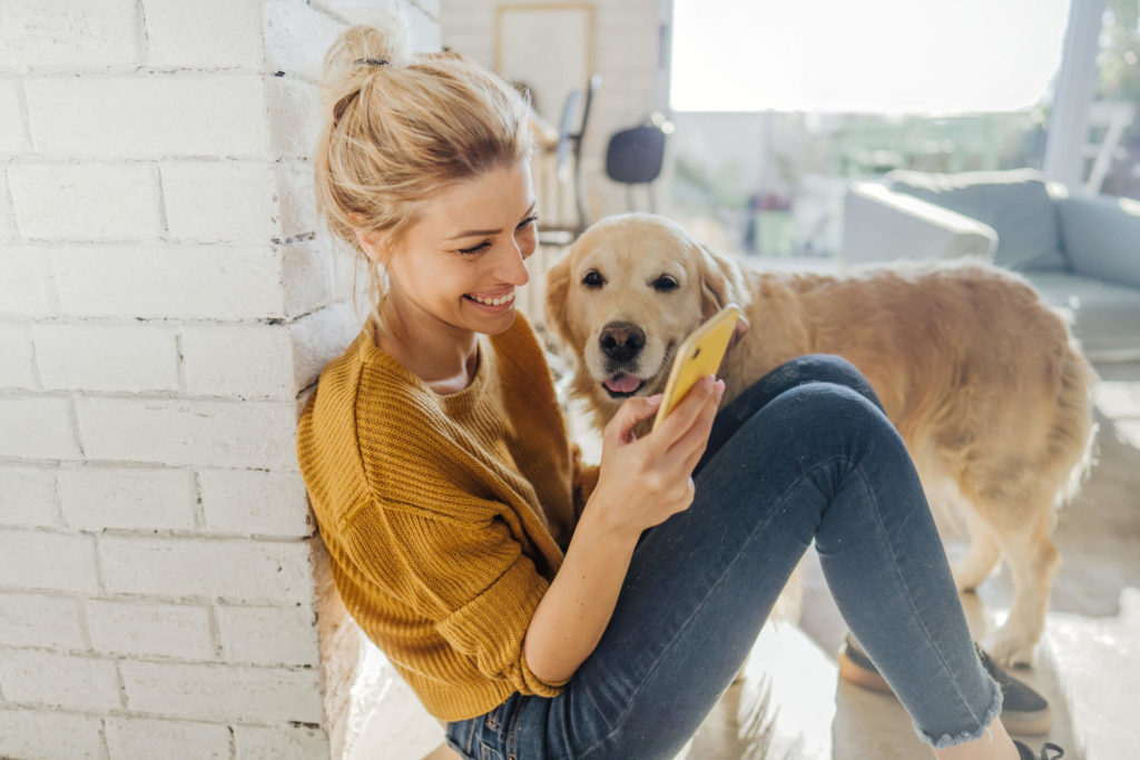 Woman using her phone with her dog