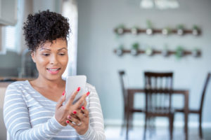 A woman sitting at home looks at her phone.