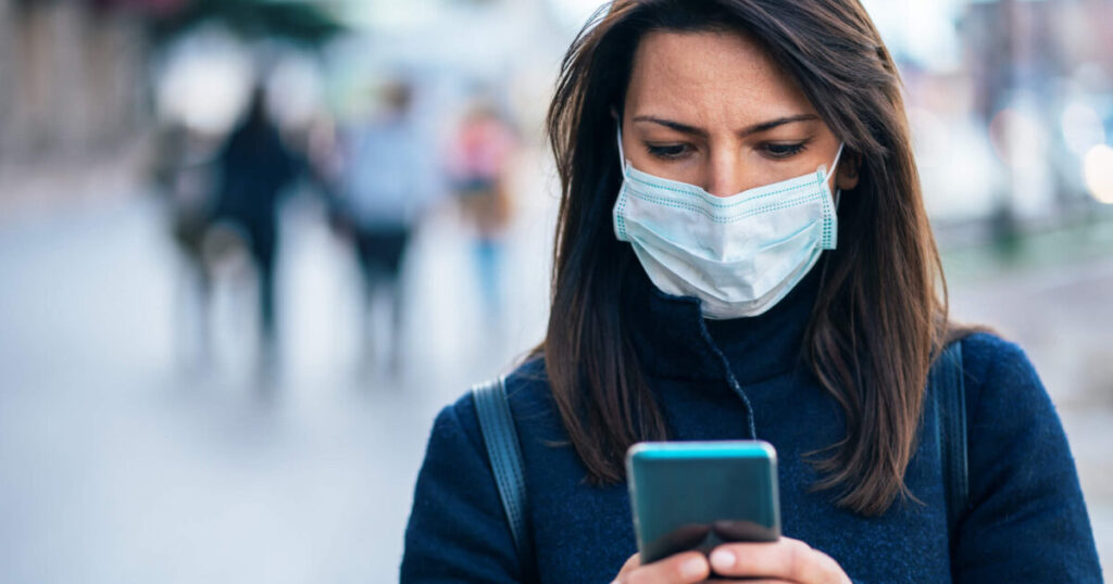 Woman using cell phone while wearing a mask.