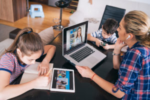 Mother trying to talk with doctor on laptop while watching two kids staying home Homeschooling and distance learning