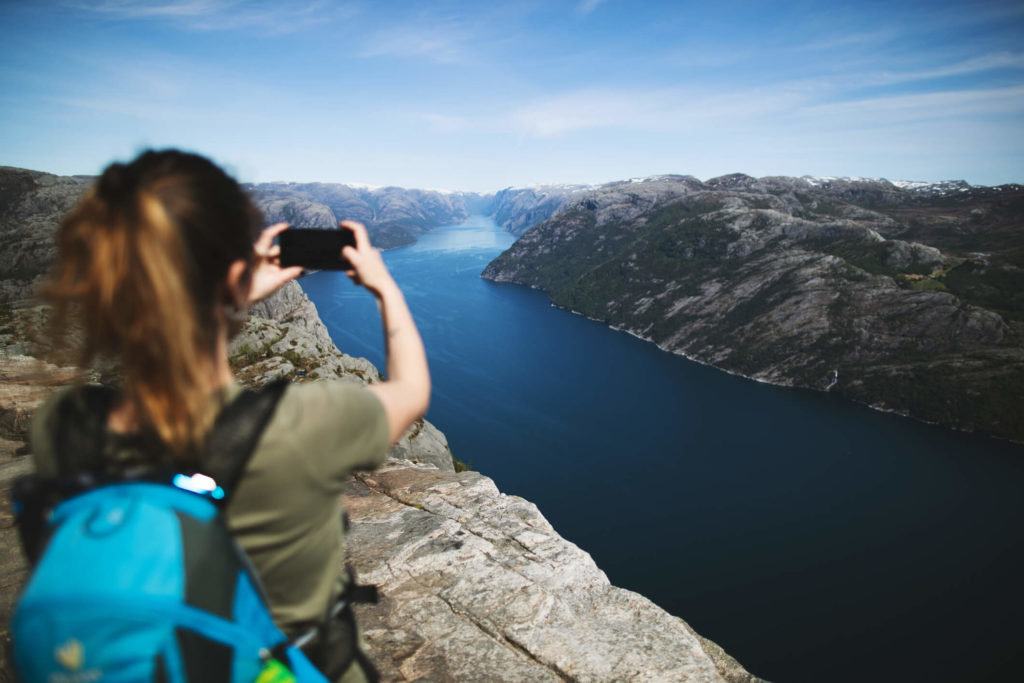 Woman uses her phone to take a photo of a beautiful river.