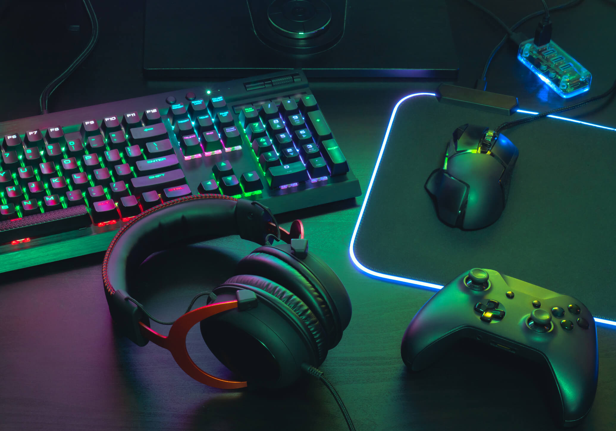 Gamer-desktop-setup-with-headphones-mouse-controller-and-RGB-keyboard-and-mousepad