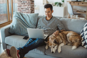 Man on laptop with dog comparing IPVanish and CyberGhost VPNs
