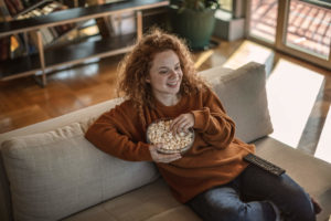 Woman eating popcorn on couch streaming media on Kodi using a VPN