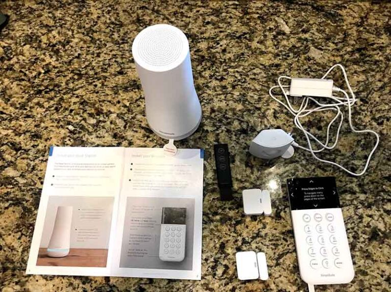 SimpliSafe equipment pictured spread out on a granite countertop next to the user guide for the system