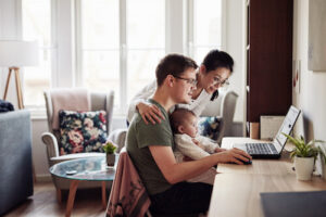 A mom, dad, and baby sit in front of a laptop together