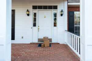 Three boxes piled in front of a white front door on a red brick porch