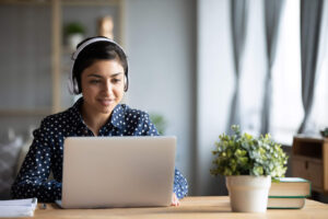 Woman works on computer at home while wearing headphones