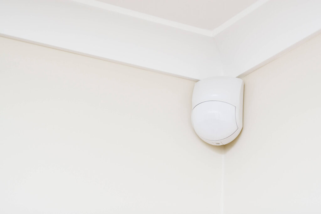 White motion sensor placed in the high corner of a white wall