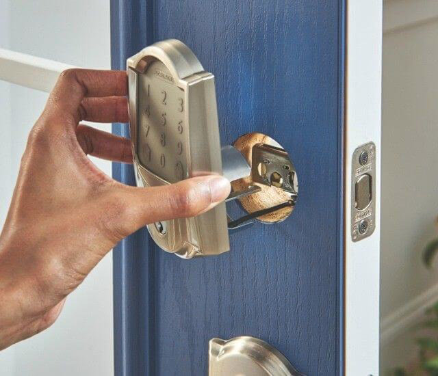 Hand holding Schlage Encode lock while installing it onto a door