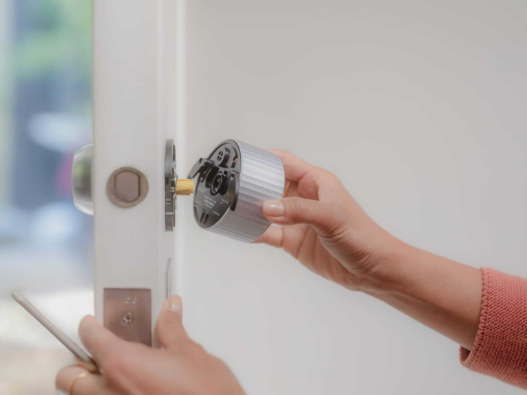 Hands attach the August Wi-Fi Smart lock to the interior of a door