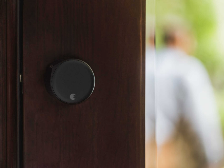 Dark-finish August Wi-Fi Smart lock installed on a dark-wood door