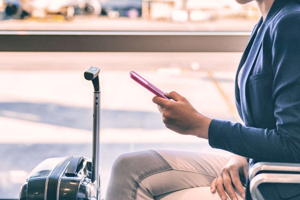 Photograph of woman using smartphone while waiting at the airport