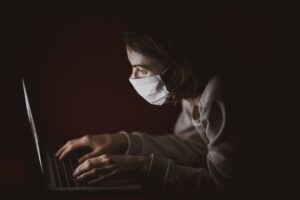 Person with medical mask uses laptop
