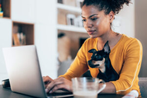 women works on computer with dog on her lap
