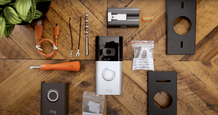 Ring Video Doorbell shown on a wooden table surrounded by the tools and accessories that come with it