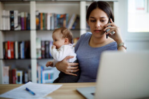 A woman looks frustrated as she talks on the phone while holding her baby