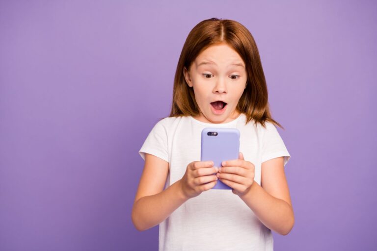 Photograph of young kid using a mobile phone on a purple background