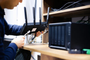 A man connects an Ethernet cable to his home router