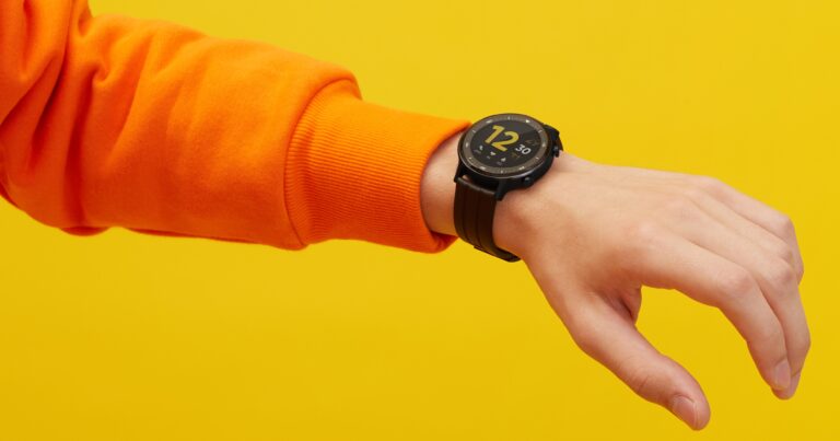 Realme Watch S on a man's wrist against a yellow background