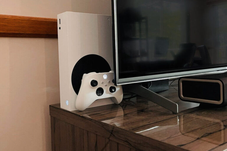 A white Xbox Series S console and controller tucked behind the author's TV