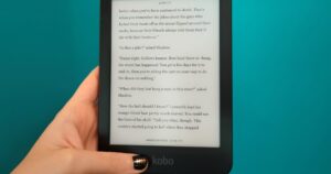 woman holding a Kobo Clara HD ereader against a blue wall