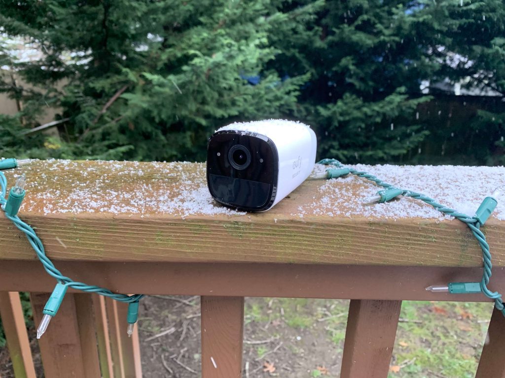 EufyCam 2 camera pictured on a deck ledge dusted with snow