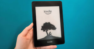 Woman holding a Kindle Paperwhite against a blue wall