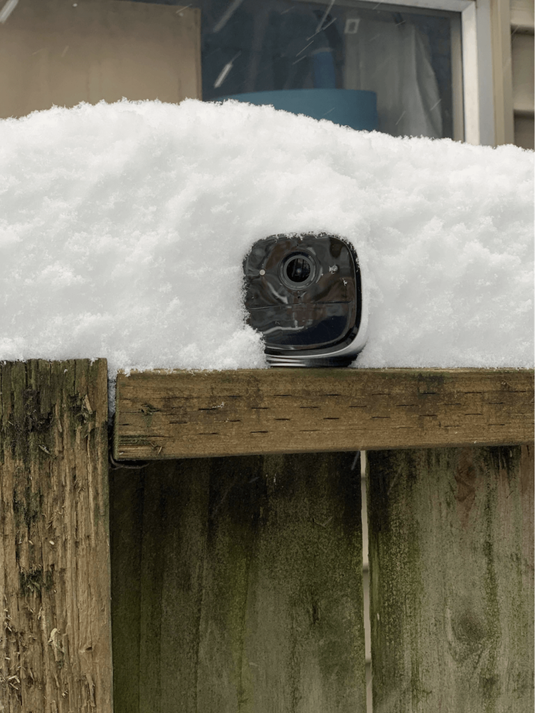 EufyCam 2 camera pictured on a fence ledge and covered in snow