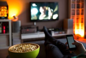 Man watching TV on living room couch eating popcorn