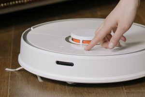 woman pressing a button on a robot vacuum or robot mop